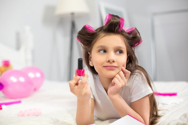 Free Photo | Cute preschooler laying on white blanket holding nail polish.