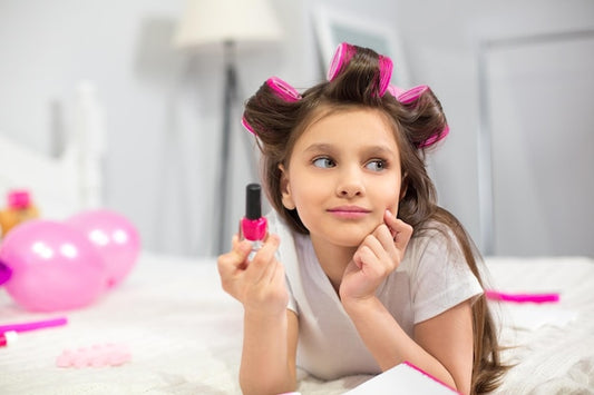 Free Photo | Cute preschooler laying on white blanket holding nail polish.